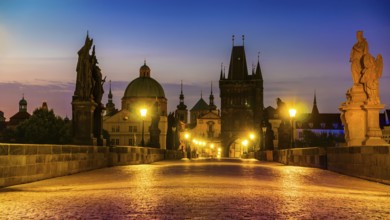 Charles Bridge illuminated with street lights at sunrise, Prague