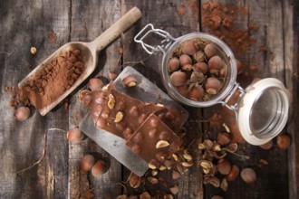 Pieces of milk chocolate with hazelnuts on wooden table
