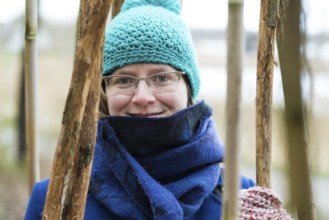 Young woman in winter clothes posing between large bamboo sticks