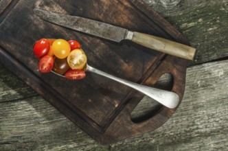 Variety of cherry tomatoes in spoon on wood