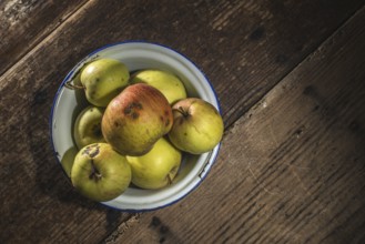 Apples in vintage metal cup on white wooden table