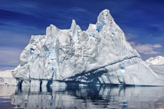 Impressive iceberg rises above a calm ocean under a blue sky, icebergs in the Southern Ocean in