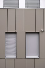 A modern office building façade with sheet metal cladding and an installed surveillance camera