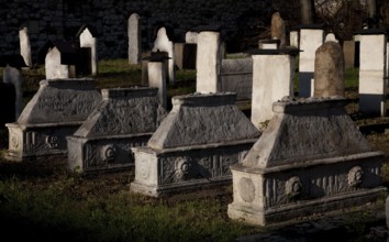 Lined up sarcophagi, tombstones behind them