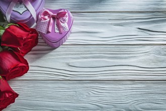 Set of metal heart-shaped present boxes red roses on wooden board celebrations concept