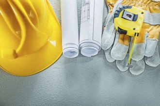 Set of blueprints building helmet safety gloves measuring tape on concrete background