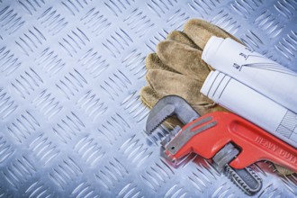 Pipe wrench engineering drawings leather safety gloves on fluted metal plate construction concept