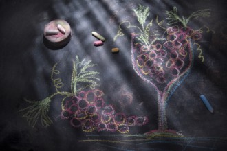 Graphical representation of a glass filled with red grapes, drawn with chalk on blackboard