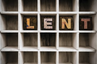 The word LENT written in vintage ink stained wooden letterpress type in a partitioned printer's