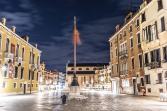Venetian flag waving in the wind, illuminated facades, Campo Santo Stefano, night shot, Venice,