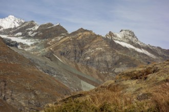 Barren mountain landscape with glaciers and snow-covered peaks under a blue sky, saas fee,