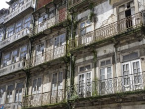 Weathered facades of old buildings with balconies and many windows, porto, portugal