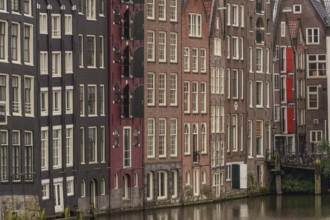 Dense row of townhouses along a canal with varied facades, Amsterdam, Netherlands