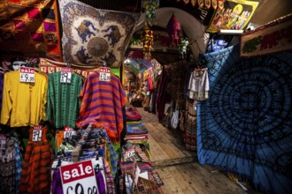 Colorful garments and textiles with sale signs in a vibrant market setting in the London Borough of