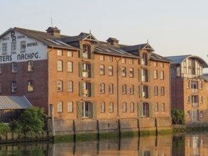 Historic brick building with several windows and reflection in the water at sunset, husum,