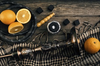 Dismantled parts of hookah on a wooden background with orange fruit. Top view. Flat lay. Copy space
