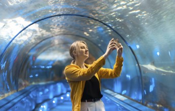 Eine Frau in einem Unterwassertunnel mit Meeresbewohnern