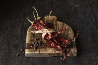 Dried chili peppers on a wooden board, dark photo