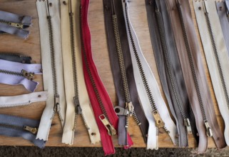 Variety of old worn used cloth zippers on a wooden board