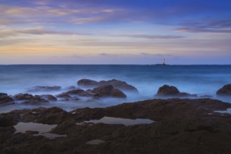 Long exposure view of the Sant'Antioco island coast and the Mangiabarche Lighthosue at sunrise on