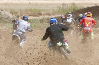 Unrecognized athletes riding a sports motorbike racing fast on a motocross track field. Challenge