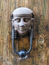 Vintage style doorknocker of an Egyptian head, a door in Italy
