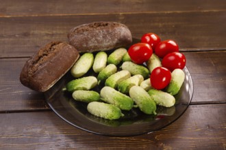 Cucumbers, Tomatoes and Rye Buns on brown wooden table