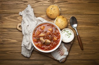 Ukrainian Borscht, red beetroot soup with meat, in white bowl with sour cream, garlic buns