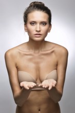 Beautiful woman in flesh color underwear showing by hand. Studio shooting