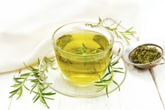 Rosemary herbal tea in a cup, a strainer with dry herb and a linen napkin on the background of a