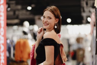 Woman smiling brightly, enjoying shopping among colorful clothes inside a store
