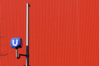 Underground symbol in front of a red, striped wall, urban traffic feeling, Vienna, Austria