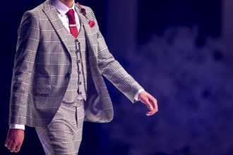 Male model walks the runway in grey suit during a Fashion Show. Fashion catwalk event showing new