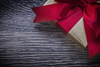 Tied wrapped gift box on wooden board holiday concept