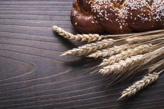 Sweet roll wheat rye ears on wooden background food and drink concept