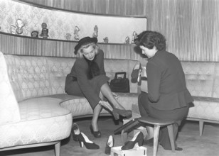 A young woman is well taken care of by a clerk in a shoe store. The dispatcher tries different