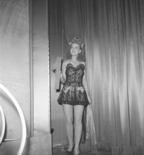 At the theatre in the 1940s. A young woman holds the number one in her hand on a theatre stage. It
