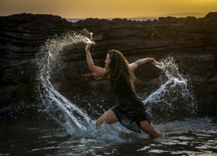 Middle-aged woman dancing and throwing water in the air, Maioris beach, llucmajor, Majorca,