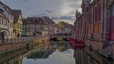 Canal running through a historic town with colorful buildings and reflections on the water, Colmar,