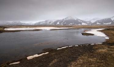 Typical Icelandic dramatic landscape with frozen lake and mountains covered in snow in Iceland
