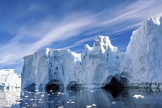 Ice formations with caves and reflections in the water under a blue sky, icebergs in the Southern