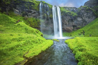 The warm July day in Iceland. Seljalandsfoss waterfall. Rainbow decorates drop of water