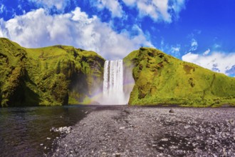 Iceland, waterfall Skogafoss summer, clouds of mist. Huge picturesque waterfall flowing from under