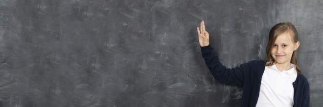 Schoolgirl shows on an empty school board. He is standing in the classroom at the chalkboard.
