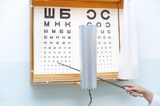 A Russian eye chart at an oculist and a hand with a pointer