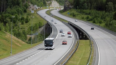 Summer motorway landscape with white Iveco Evadys tour bus among car traffic. Salo, Finland, June