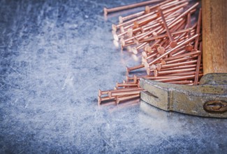 Vintage claw hammer copper construction nails on metallic background