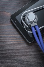 Medical stethoscope and touch-sensitive pad on vintage wooden background medicine concept