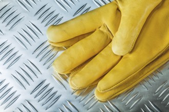 Pair of leather safety gloves on corrugated metal texture