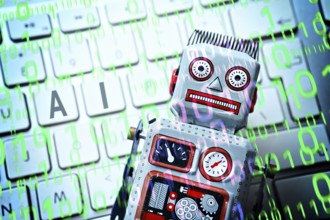 Robot on computer keyboard, symbolic photo of artificial intelligence, photomontage
